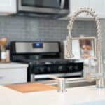 Brushed nickel faucet and fixture next to a sink in a kitchen